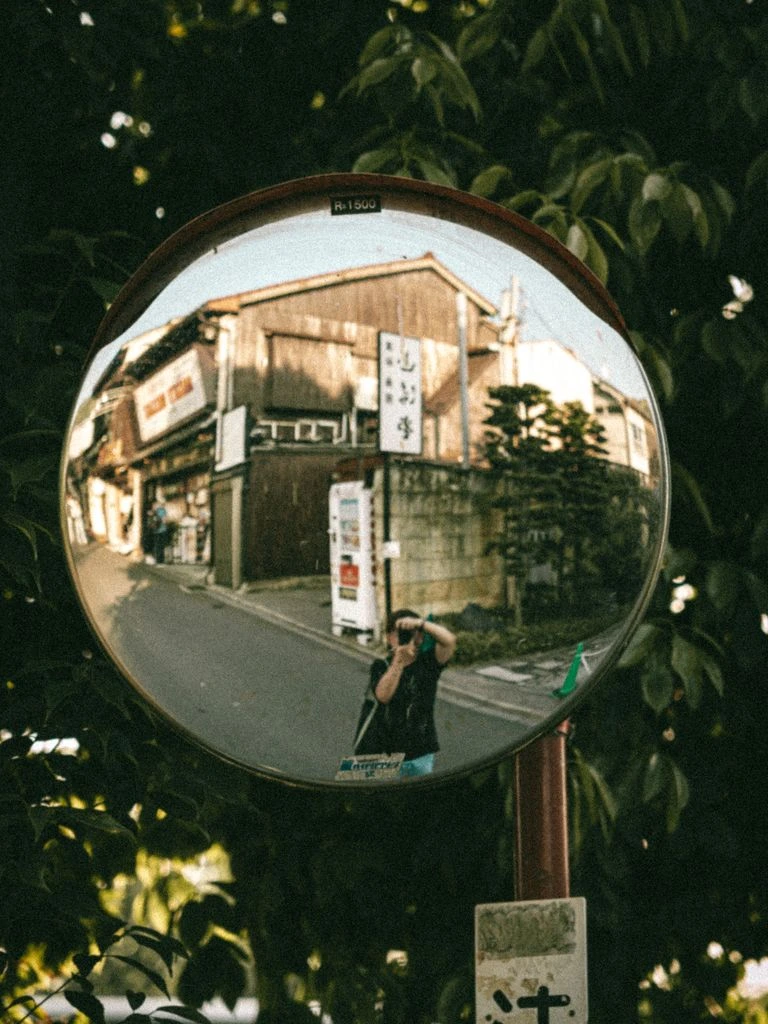 A narrow Kyoto side street at dawn, viewed from an open wooden window.