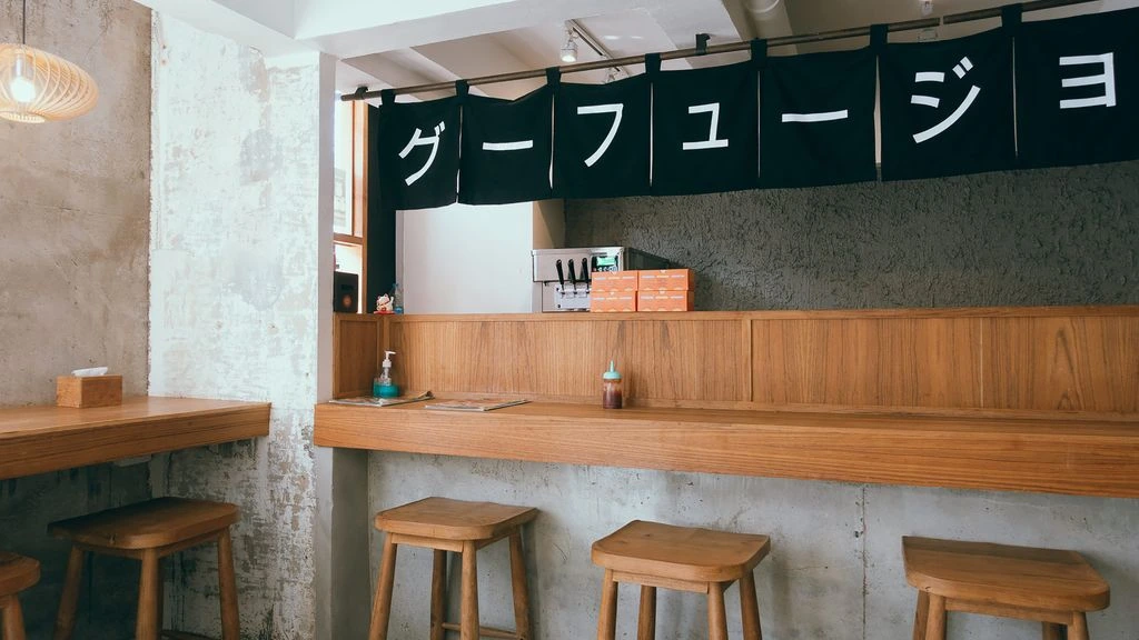 A neighborhood izakaya counter in east Tokyo, with handwritten menus taped to the wall.